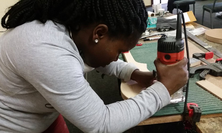 A student works meticulously to build a dulcimer guitar.