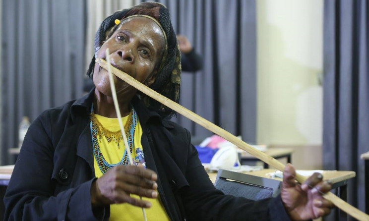 Bavikile Ngema shows workshop participants how to play an umakhweyana.